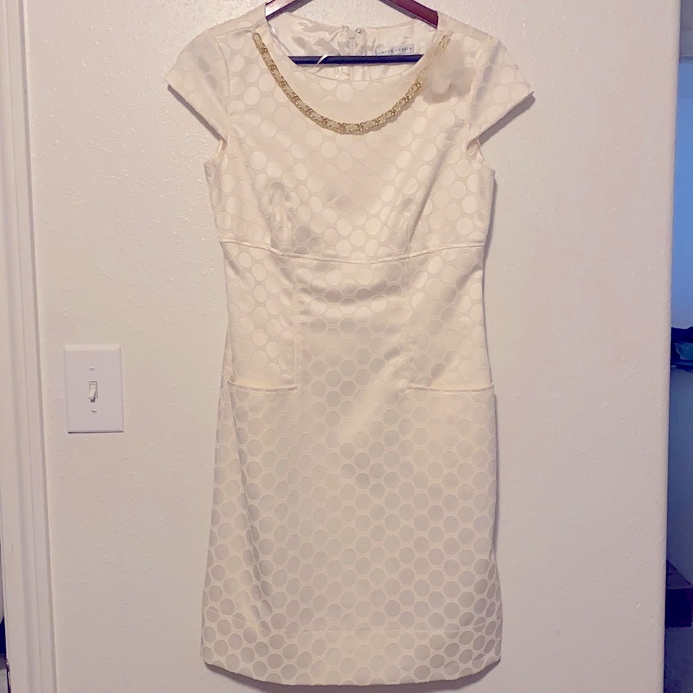 White mid-length zip up dress with gold necklace.